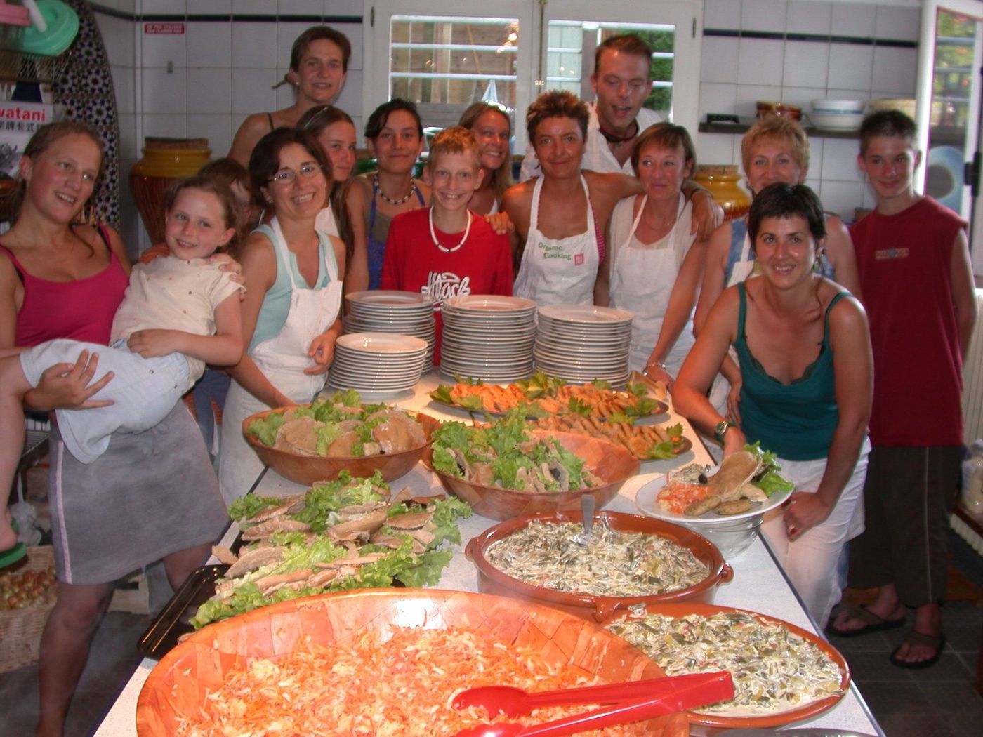 Grupo de participantes numa cozinha diante de um grande bufete